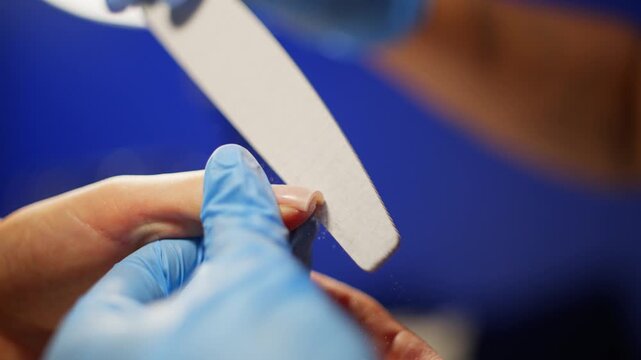 The manicurist makes calm, balanced movements with the file while shaping the beautiful shape of the nail. High quality 4k footage