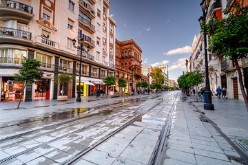 Naklejka premium Main Street in Seville with colorful houses and people, life on the streets of the Spanish city, Andalusia.