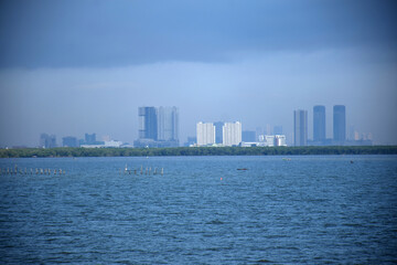 Obraz premium From a distance, the land stretches with the ever-growing number of high-rise buildings standing on the east coast of Surabaya, Indonesia.