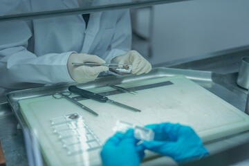 Pathology lab tool for tissue biopsy processing. Scientists using surgical scissors to prepare histology samples in sterile cabinet securely. Medical preparing tissue cassettes for histology analysis.