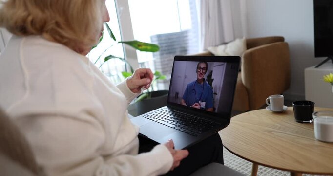Senior patient consulting with a female physician via video call on a laptop from her home, receiving remote medical advice and showing her medication during the online appointment