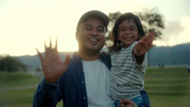 Father and son wave their hands goodbye to the camera with warm smiles and joyful family moment strong bonding with quality time and childhood happiness, Father&rsquo;s Day celebration concept.
