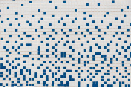 A full-frame, close-up photograph of a modern mosaic tile wall or floor with a random, pixelated pattern of small white and blue square tiles. This geometric background