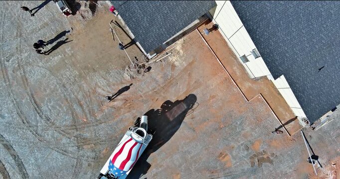 Aerial view of construction site with workers, heavy machinery, cement mixed vehicle featuring US patriotic design.
