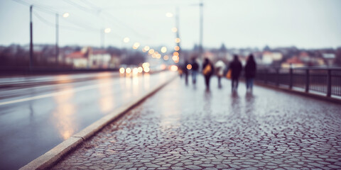 Obraz premium Rainy street urban scene with blurred commuters walking on cobbled pavement and glowing city lights reflecting on wet road