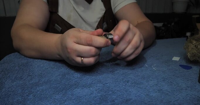 Professional plumber's hands carefully wrapping oakum fiber around the threads of a metal pipe fitting to create a watertight seal, showing a detailed view of the plumbing maintenance process.