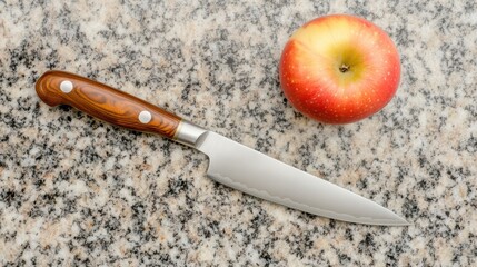 A red apple beside a shiny knife on a granite surface