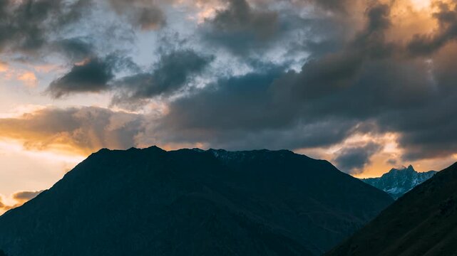 Dramatic Himalayan Mountain Silhouette at Sunset with Moving Clouds and text Copy Space. High Contrast Atmospheric Nature Background of Orange Sunset and Dark Terrain
