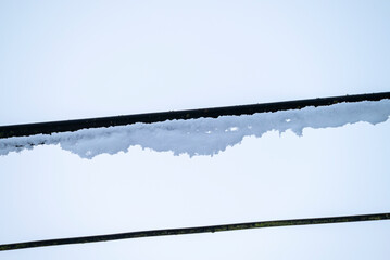 Close up of snow accumulated on black power lines The Concept of Frost