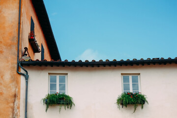 Traditional Italian window and colorful building facade with shutters and hanging laundry, everyday life and architecture details in Italy