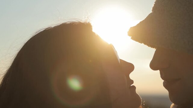 Silhouette of romantic couple cuddling and kissing in sunset winter park closeup. Happy man and woman share love feelings embracing at dusk countryside. Young family relationship