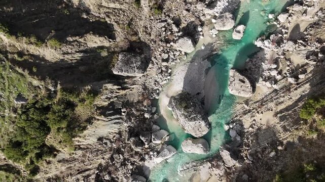 Close-up drone perspective of a wild river bed in Albania. White limestone rocks create a dramatic contrast with the bright turquoise water. Perfect as a nature background or for themes related to env