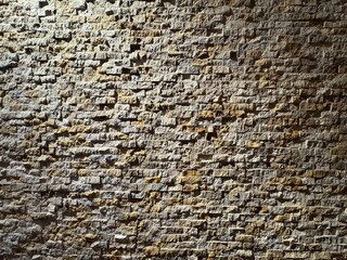 Natural stone brick wall texture background. Stone brick wall texture, uneven surface, warm neutral tones. Background for architecture, interior design, wallpaper, construction, and vintage.