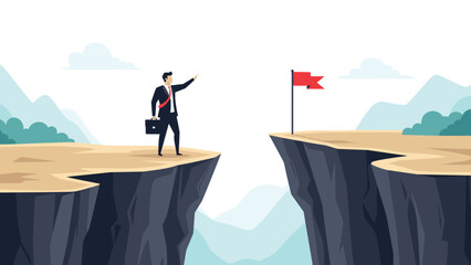 Obraz premium Businessman standing at the edge of a deep canyon looking across at a target flag in a metaphor for business risk and challenges.