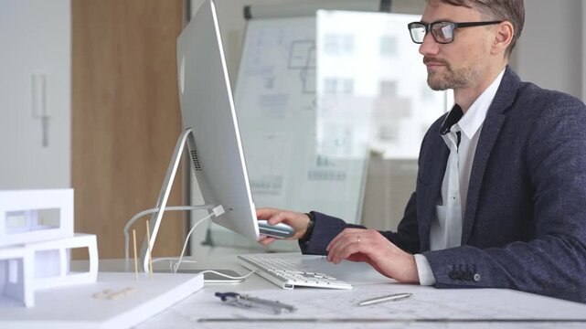 Architect working on computer creating building design, drafting construction plans, modeling house layout. Business and architecture concept