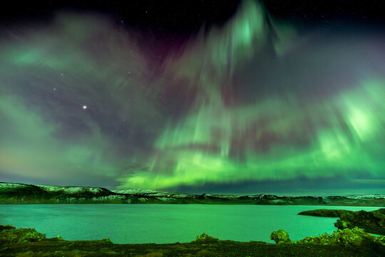 View of vibrant green and purple Northern Lights dance over the tranquil waters of Kleifarvatn, painting the Icelandic night sky, Kleifarvatn, Grindavikurbaer, Iceland.