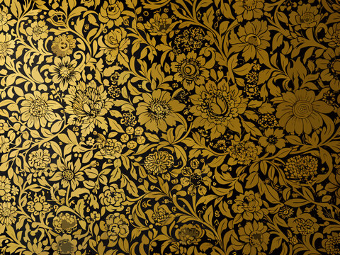 Intricate floral pattern in gold and black reminiscent of william morris