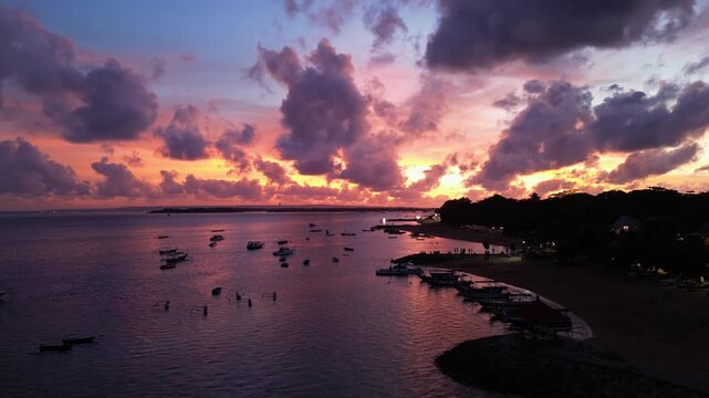 Sanur, Bali: Aerial drone footage of dramatic sunset over sanur beach in Bali, Indonesia. Taken with forward motion showing coastline and traditional Jukung wooden boats in the sea