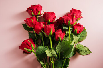 Valentine's Day background. Red roses flowers in heart shaped bouquet over pink background. Abstract flat lay. Celebrate, festive greeting card.