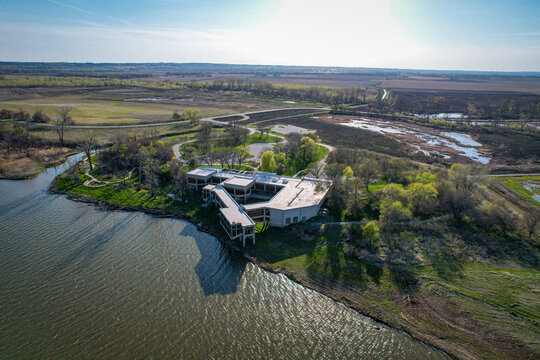 Aerial view of a modern building with angular roofs nestled between the Missouri River and the wetlands under a vast sky, Missouri Valley, Iowa, United States.