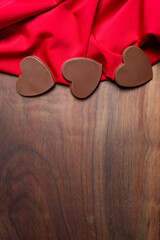 Chocolate Candy Hearts Symbolizing Love on Red Fabric with wood Copy Space