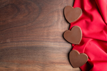 Chocolate Candy Hearts Symbolizing Love on Red Fabric with wood Copy Space