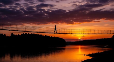 Fototapeta premium Person walking on suspension bridge at sunset.