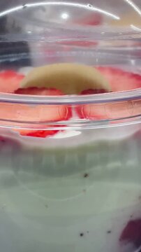 layered yogurt parfait cups deli clerk stocking refrigerated shelf clear lids reveal granola, berry compote, creamy yogurt layers, honey drizzle, portable Video taken on mobile device.