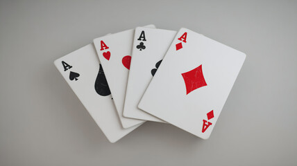 Obraz premium Four aces playing cards with spade, diamond, club and heart suits on a grey background, playing cards on a white background, four aces , ace of heartsx, royal flush poker cards, royal flush of spades,