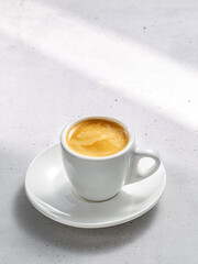 A serene coffee set with one cup on a saucer on a stone under the gentle sunlight
