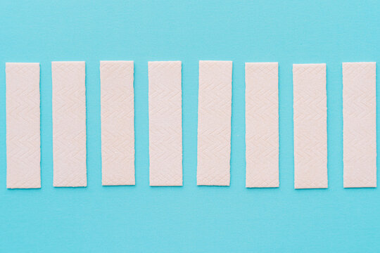 Chewing gum sticks aligned on turquoise background, minimal composition. High quality photo