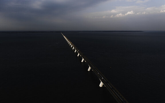 Aerial view of a seemingly endless bridge stretching across dark waters beneath a sky of brooding clouds, Zierikzee, Zeeland, Netherlands.