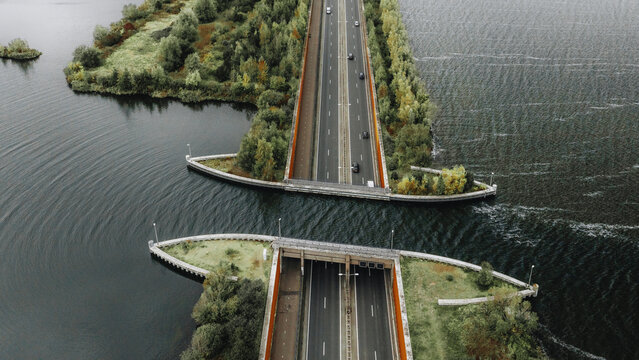Aerial view of the Veluwemeer Aquaduct, where the road seems to float above the serene waters, surrounded by the autumnal hues of Gelderland, Harderwijk, Gelderland, Netherlands.