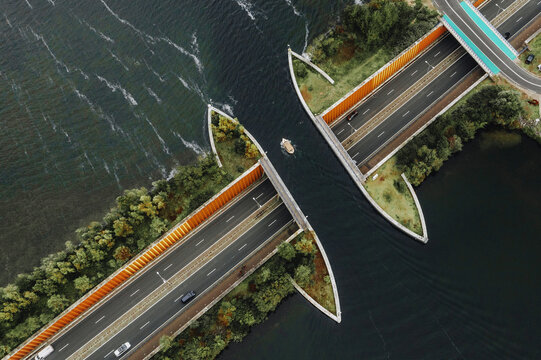 Aerial view of the Veluwemeer Aquaduct, where the road dramatically parts to allow boats to pass, creating a striking contrast against the dark water, Harderwijk, Gelderland, Netherlands.