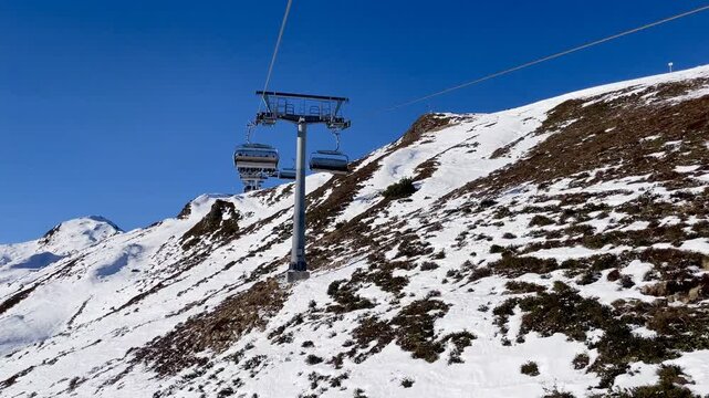Ski resort with insufficient snow seen from a chairlift, illustrating the impact of climate change on winter tourism.