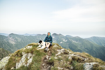 Fototapeta premium woman trekking with a dog in high mountains