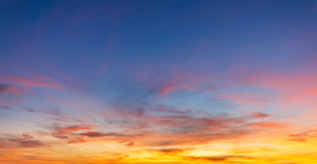 Fototapeta premium Beautiful sunset sky with colorful pink and orange clouds at twilight background,Spectacular sunset sky featuring soft wispy clouds in vibrant shades of pink, orange, and blue. A serene and peaceful.