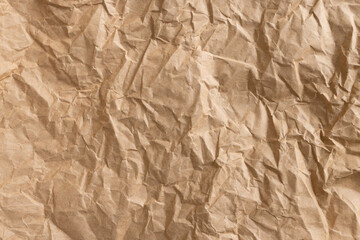 Fototapeta premium Crumpled brown kraft paper background macro,High-angle view of a sheet of crumpled brown kraft paper with heavy creases and wrinkled texture. This vintage-style aesthetic background is perfect.