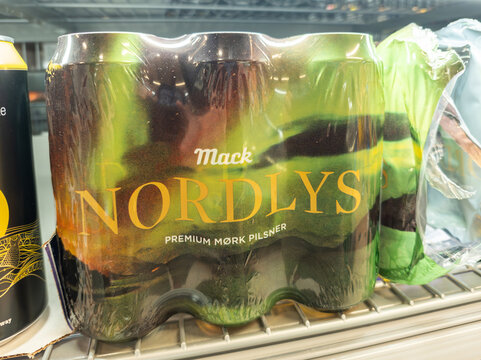 18 july 2025, Ramberg, Norway. View on shelf in the supermarket with beer cans from Mack Nordlys beer, wrapped in colored plastic, photo of northern lights. Beer containing alcohol.