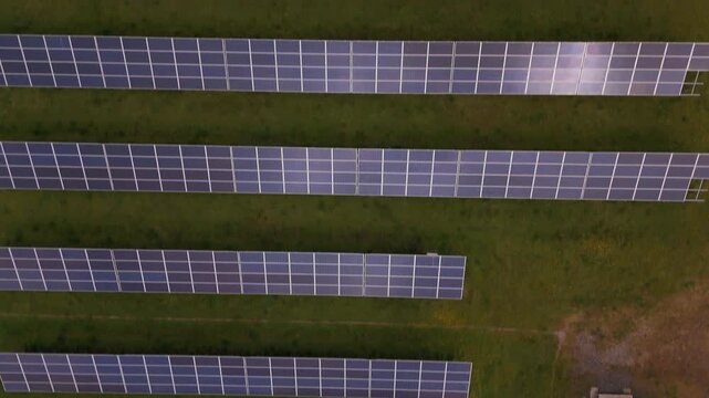 Aerial view of neatly arranged rows of solar panels on a green field creating a geometric pattern of blue and green, Perth, Scotland, United Kingdom.