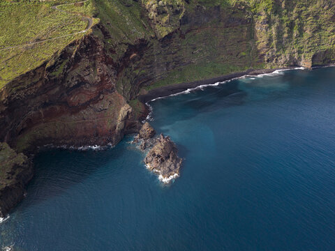 Aerial view of the rugged coastline where dark volcanic cliffs meet the turquoise ocean, Playa de Nogales, La Palma, Canary Islands, Spain.