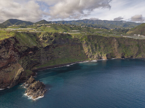 Aerial view of the rugged famous Playa de Nogales coastline meets the deep blue sea, framed by verdant cliffs and distant mountains, La Palma, Canary Islands, Spain.