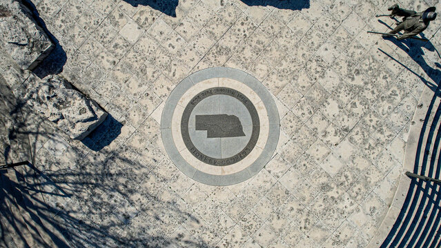 Aerial view of Nebraska state emblem on a patterned stone surface with shadows dancing across, Omaha, Nebraska, United States.