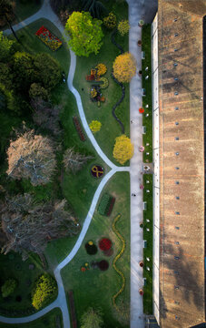 Aerial view of winding paths and vibrant flowerbeds contrasting with the stark geometry of the building in Parc de l'Independance, Morges, Vaud, Switzerland.