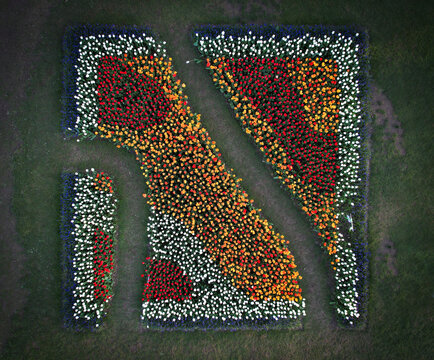 Aerial view of meticulously arranged flowers forming a striking design, with pathways cutting through the floral tapestry in Parc de l'Independance, Morges, Vaud, Switzerland.