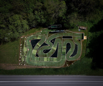 Aerial view of a mini RC circuit track with its intricate green and black design nestled among the trees, Eclepens, Vaud, Switzerland.
