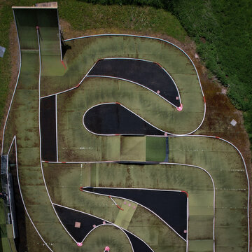 Aerial view of Circuit Mini RC, a winding track of green and black asphalt, framed by concrete barriers, Eclepens, Vaud, Switzerland.