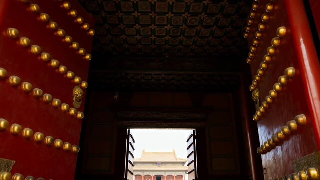 Latch releasing red gates swinging inward at palace gate, revealing distant hall with lion knockers
