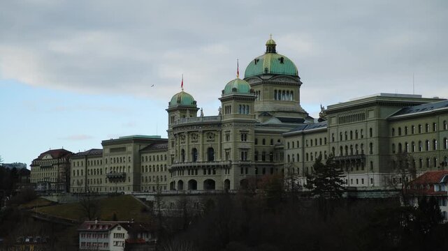 The imposing facade and iconic green-domed towers of the Swiss Federal Palace in Bern stand prominently against a soft evening sky, showcasing the grand Neo-Renaissance architecture of Switzerland's s