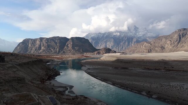 Aerial view of the Indus River flowing through a rugged landscape, contrasting the turquoise water with the barren mountains, Skardu, Gilgit Baltistan, Pakistan.